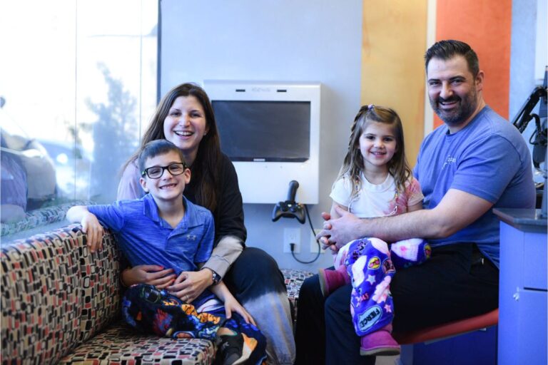 northport-orthodontics-smiling-patient Adult and two children sitting and smiling in a clinic waiting area