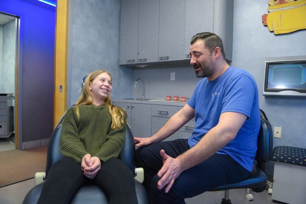 doctor talking with smiling young female patient about braces in northport